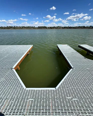 Metal dock over a calm, green lake.