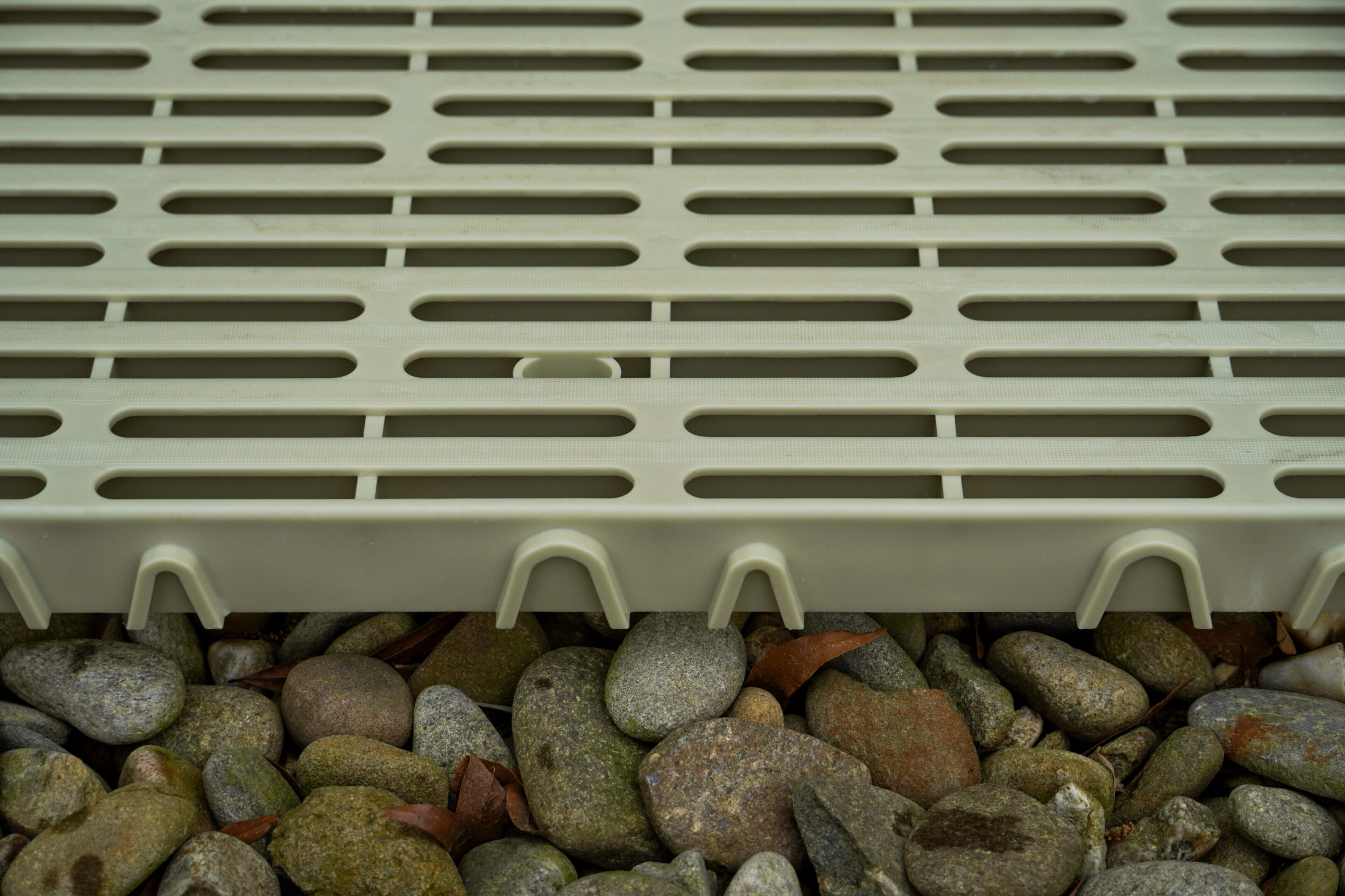 Plastic grate above pebbles and stones.