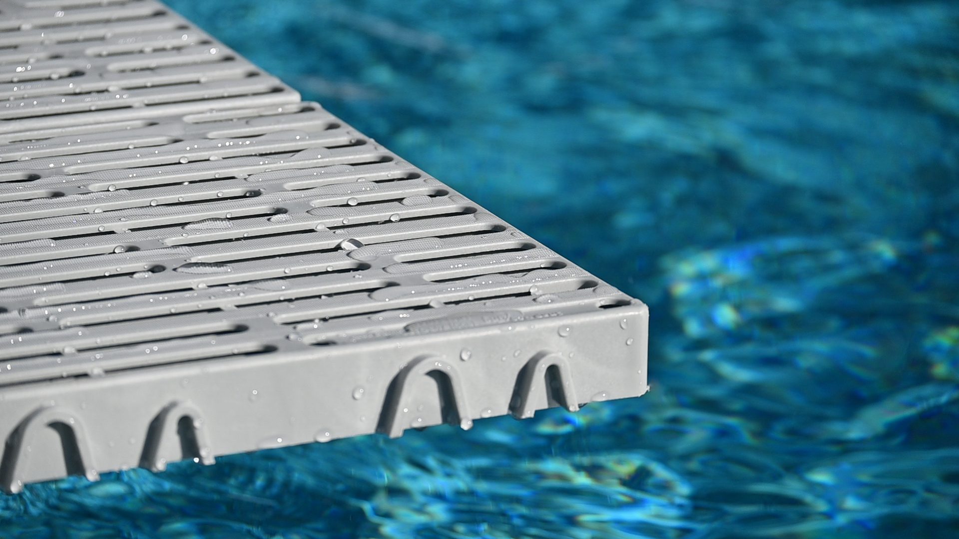 Poolside grating above clear blue water.