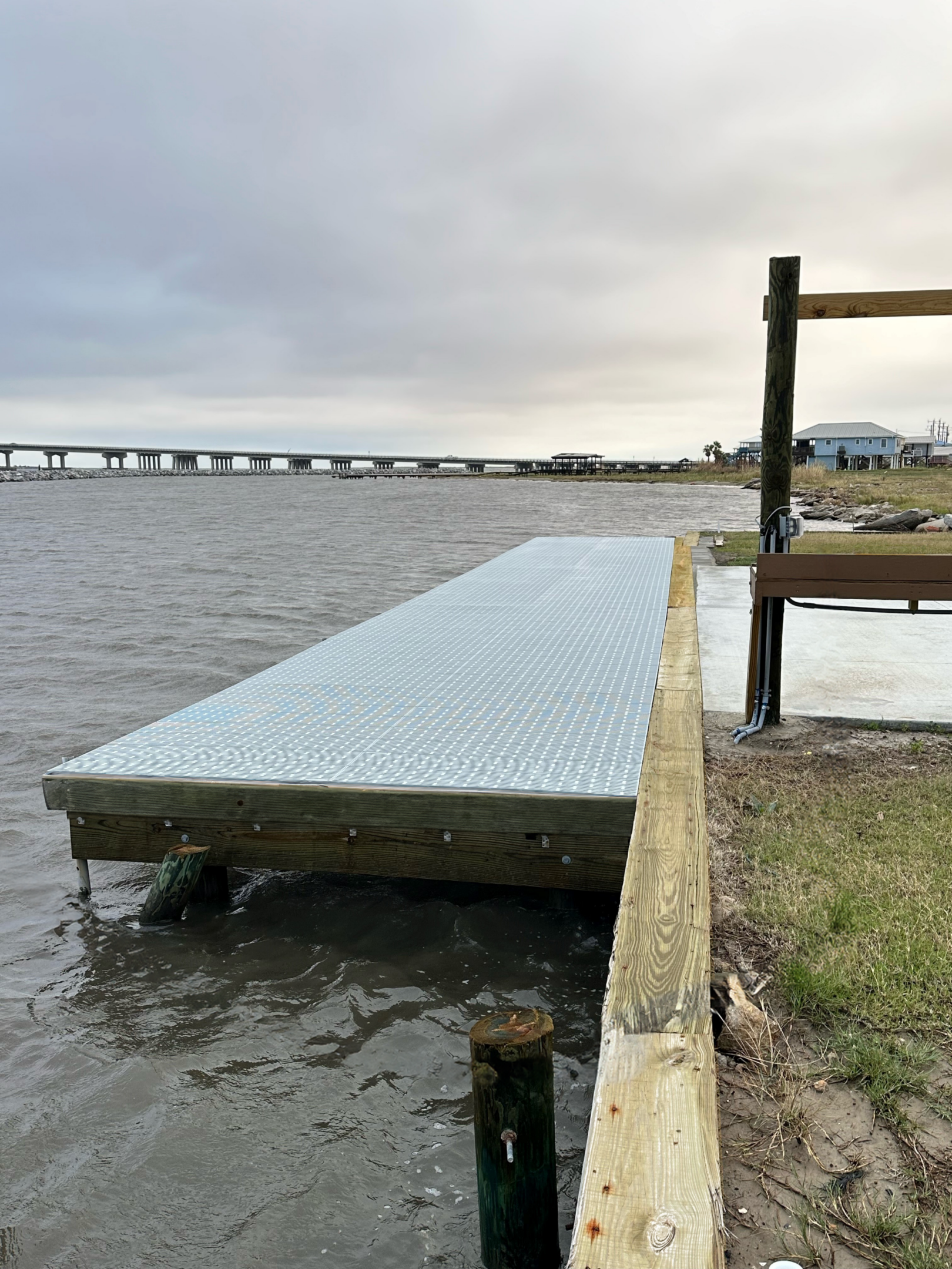 Metal dock extending over calm waterfront view.